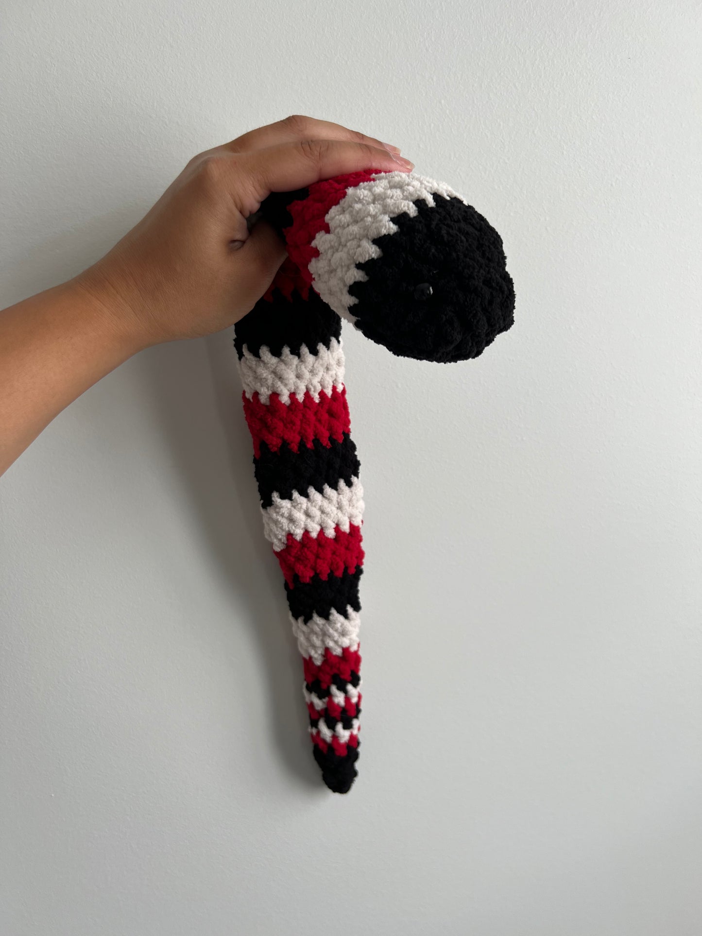 Black, red and white snake snuggler